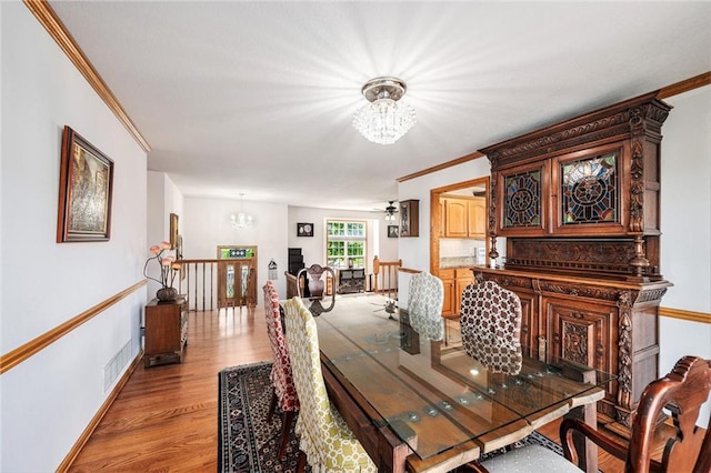 dining area featuring a chandelier, crown molding, light wood-type flooring, and baseboards