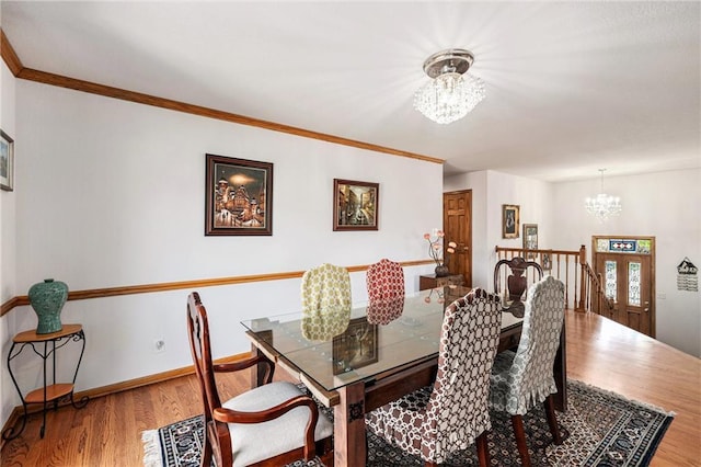 dining area featuring a chandelier, wood finished floors, ornamental molding, and baseboards