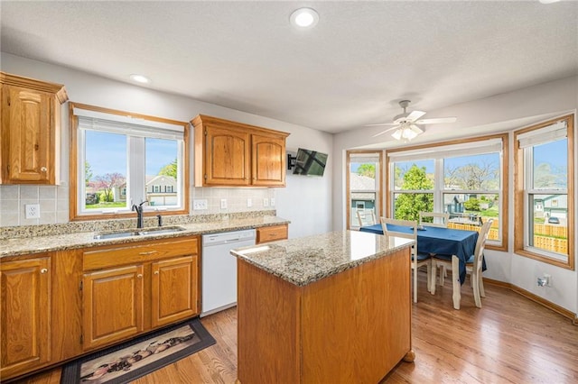 kitchen with white dishwasher, a sink, a center island, decorative backsplash, and recessed lighting