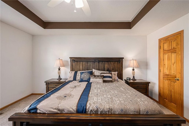 carpeted bedroom with baseboards, a raised ceiling, and a ceiling fan