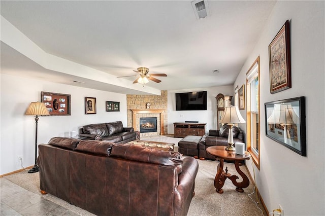 living area featuring ceiling fan, baseboards, and a fireplace
