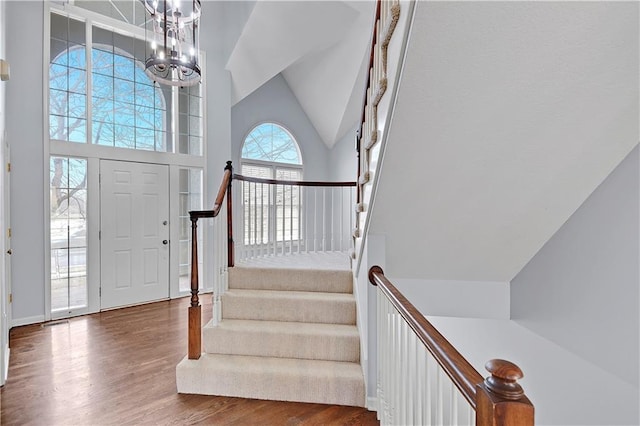 entrance foyer featuring dark wood-style floors, stairway, a chandelier, and high vaulted ceiling