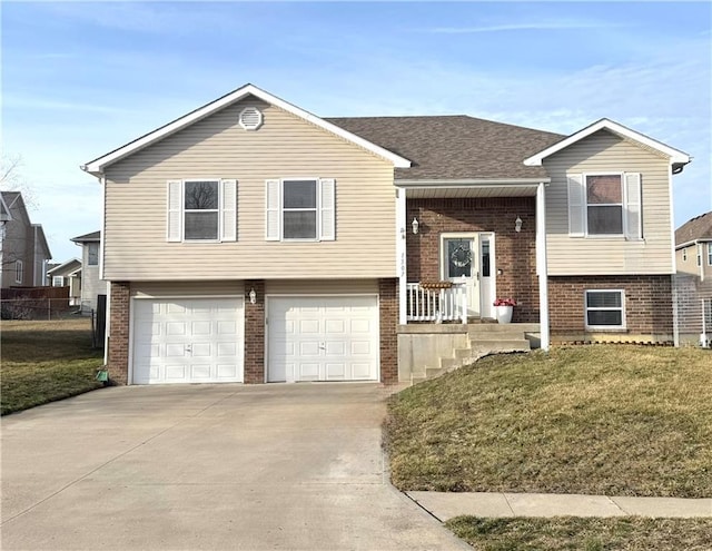 bi-level home with brick siding, a garage, concrete driveway, and a front lawn