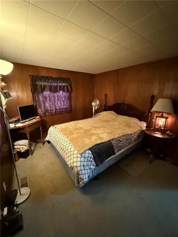 bedroom with carpet and wooden walls