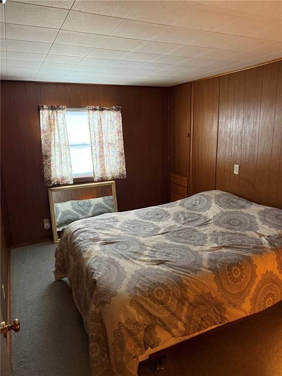 bedroom featuring carpet floors and wood walls