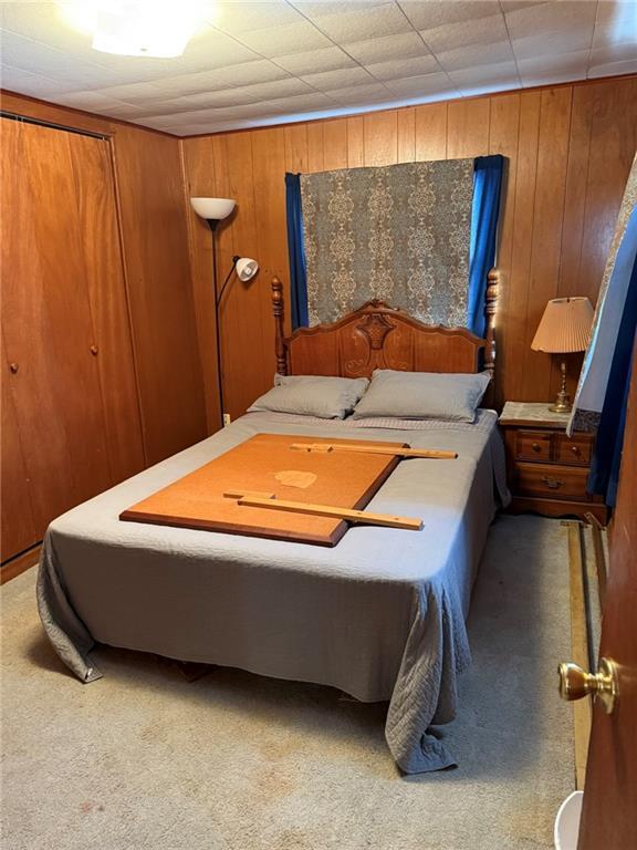 bedroom featuring carpet flooring and wood walls