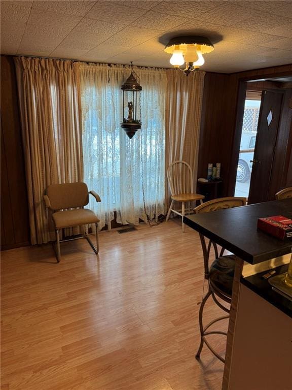 dining room featuring light hardwood / wood-style flooring and wood walls