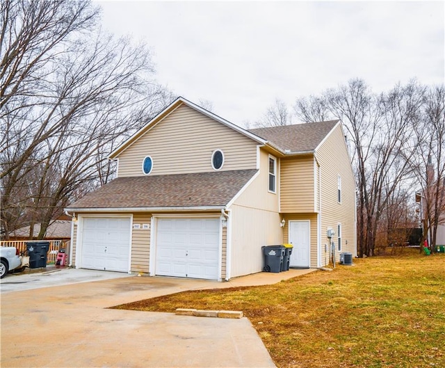 view of side of property featuring a garage, a lawn, a shingled roof, and central air condition unit