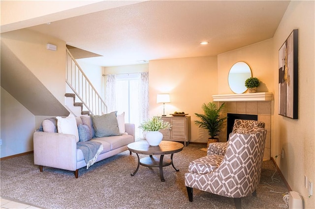 carpeted living area with stairs, recessed lighting, a tile fireplace, and baseboards