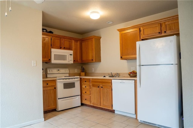 kitchen with white appliances, brown cabinets, light countertops, a sink, and light tile patterned flooring