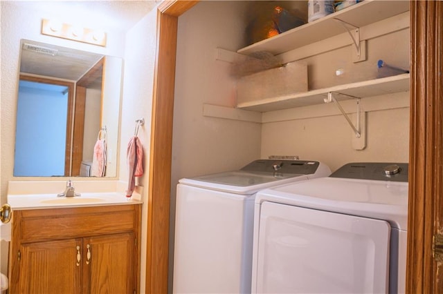 clothes washing area with laundry area, visible vents, washer and clothes dryer, and a sink