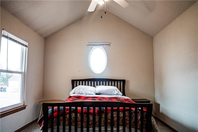 carpeted bedroom featuring lofted ceiling, multiple windows, a ceiling fan, and baseboards