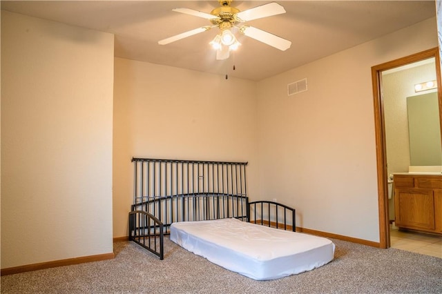 bedroom with ceiling fan, ensuite bathroom, light carpet, visible vents, and baseboards