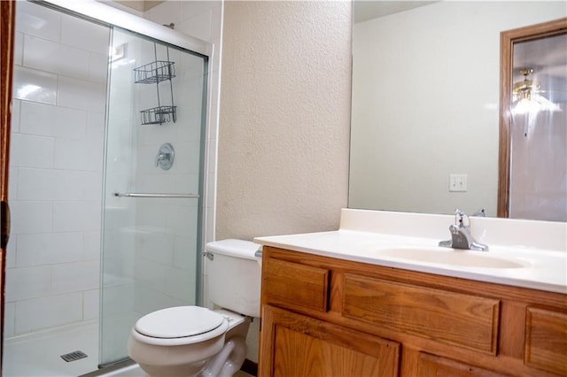 full bath with a textured wall, vanity, toilet, and a shower stall