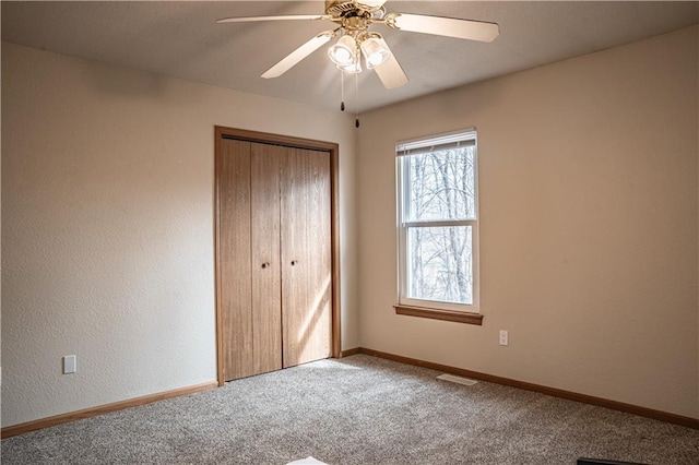 unfurnished bedroom with ceiling fan, a closet, carpet flooring, and baseboards