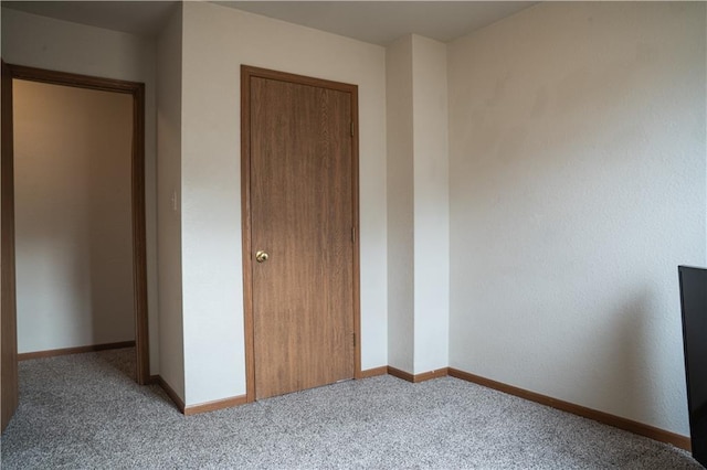 unfurnished bedroom featuring carpet floors, a closet, and baseboards