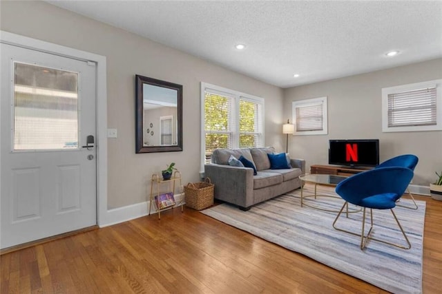 living room featuring a textured ceiling, recessed lighting, wood finished floors, and baseboards