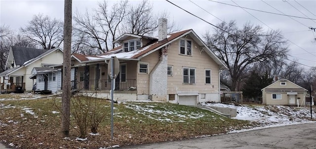 snow covered property with a garage and covered porch