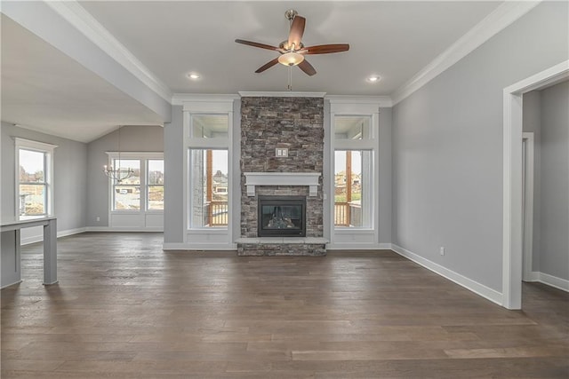 unfurnished living room featuring crown molding, a stone fireplace, dark wood-type flooring, and ceiling fan with notable chandelier