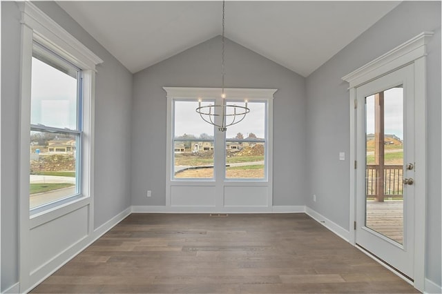 unfurnished dining area featuring hardwood / wood-style flooring, lofted ceiling, and a chandelier