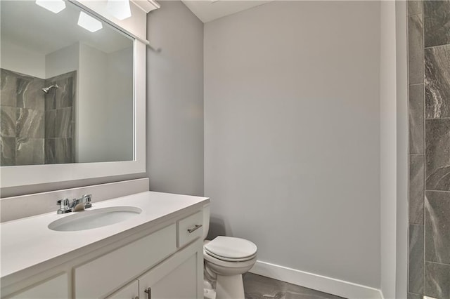 bathroom featuring vanity, tiled shower, and toilet