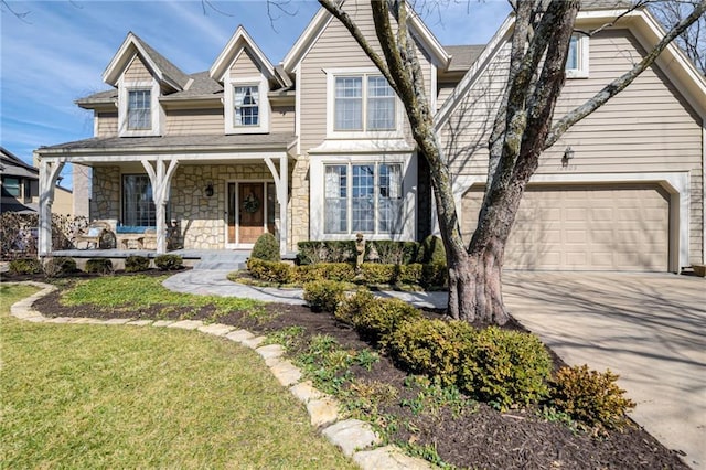 view of front of property with stone siding, a front lawn, a porch, and driveway