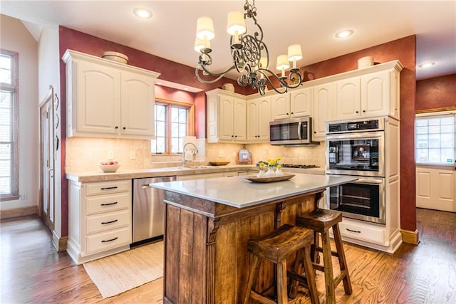 kitchen featuring a chandelier, a healthy amount of sunlight, appliances with stainless steel finishes, and light wood finished floors