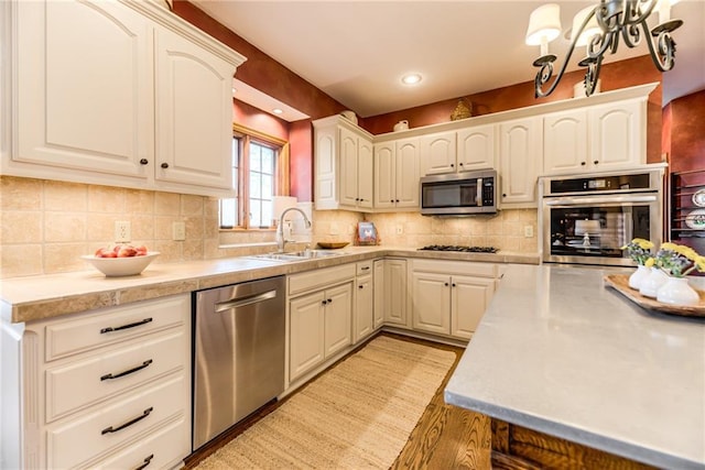 kitchen featuring a sink, backsplash, recessed lighting, appliances with stainless steel finishes, and light countertops