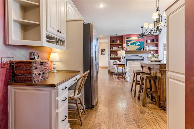 interior space featuring built in features, light wood-style flooring, a fireplace, recessed lighting, and a chandelier