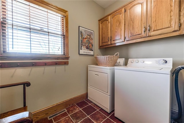 laundry room with baseboards, visible vents, dark tile patterned flooring, cabinet space, and washer and clothes dryer