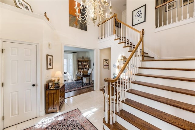 foyer featuring tile patterned flooring, a notable chandelier, stairs, and a high ceiling