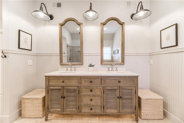 bathroom featuring a sink, visible vents, and wainscoting