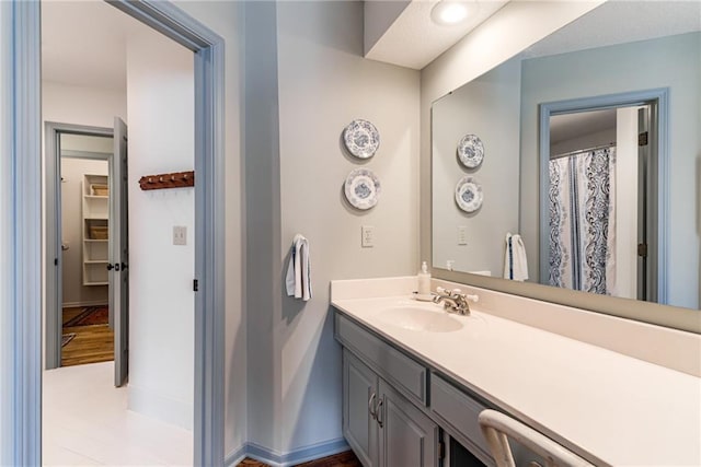 full bath featuring baseboards and vanity