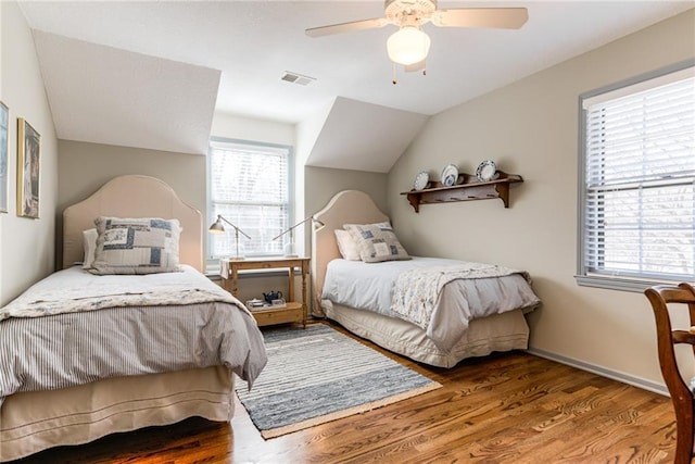 bedroom featuring visible vents, baseboards, vaulted ceiling, wood finished floors, and a ceiling fan