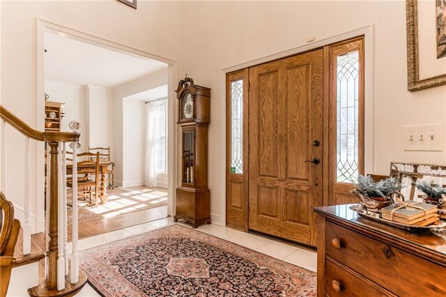 entrance foyer featuring stairs, light tile patterned flooring, and baseboards