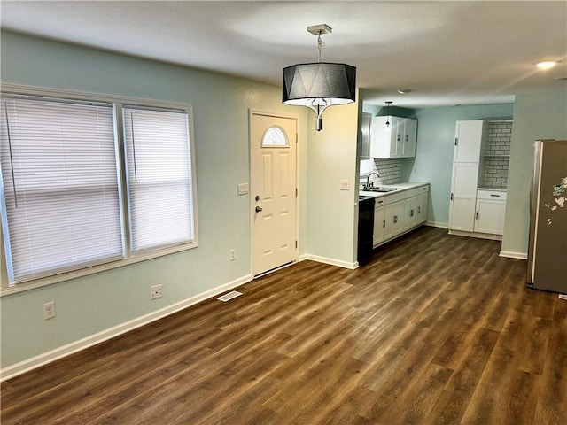 kitchen with decorative light fixtures, dishwasher, white cabinetry, sink, and stainless steel fridge