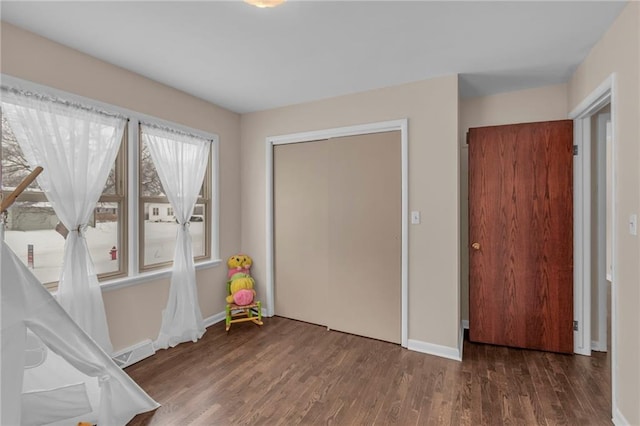 unfurnished bedroom with dark wood-style floors, a closet, and baseboards