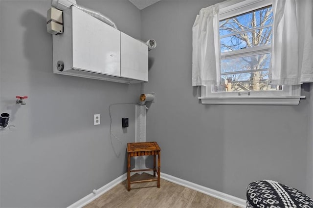 laundry area featuring cabinet space, light wood-style flooring, and baseboards