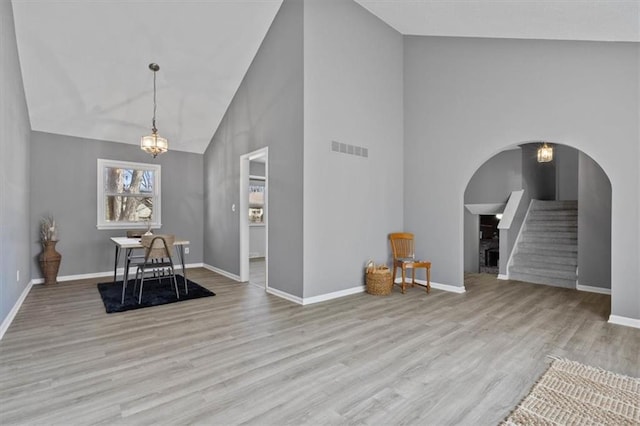 unfurnished dining area featuring arched walkways, stairway, wood finished floors, and visible vents