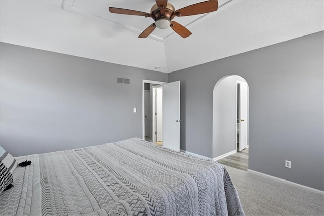 bedroom featuring baseboards, visible vents, arched walkways, lofted ceiling, and carpet floors