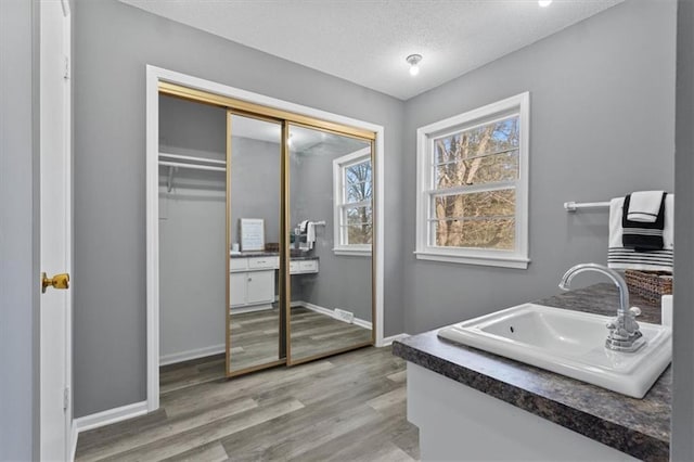 bathroom featuring a textured ceiling, wood finished floors, vanity, and baseboards