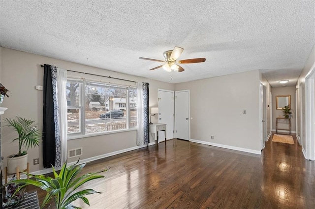 interior space featuring ceiling fan, dark wood-type flooring, and a textured ceiling