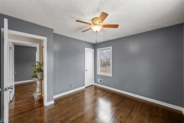 unfurnished room with a textured ceiling, dark wood-type flooring, and ceiling fan