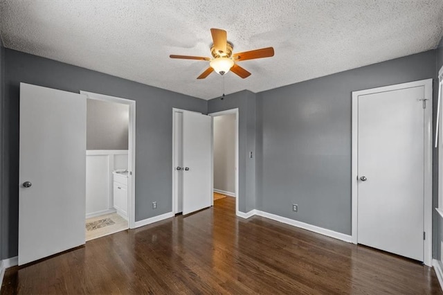 unfurnished bedroom featuring a textured ceiling, dark wood-type flooring, and ensuite bathroom