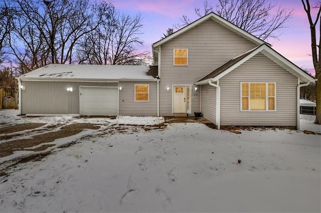 snow covered rear of property featuring a garage