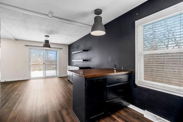 kitchen featuring a textured ceiling, butcher block countertops, dark wood-style flooring, dark cabinetry, and open shelves