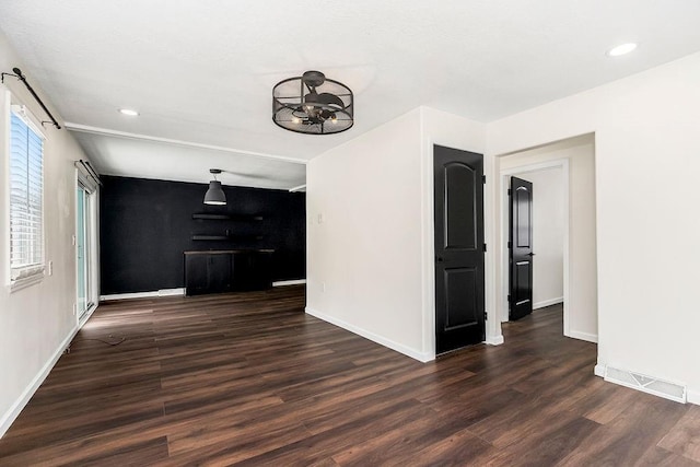 unfurnished living room featuring dark wood-style floors, baseboards, visible vents, and recessed lighting