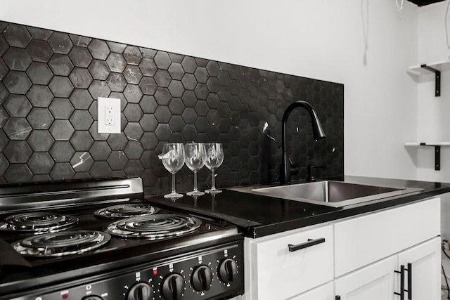 kitchen with black electric range, dark countertops, white cabinets, and a sink