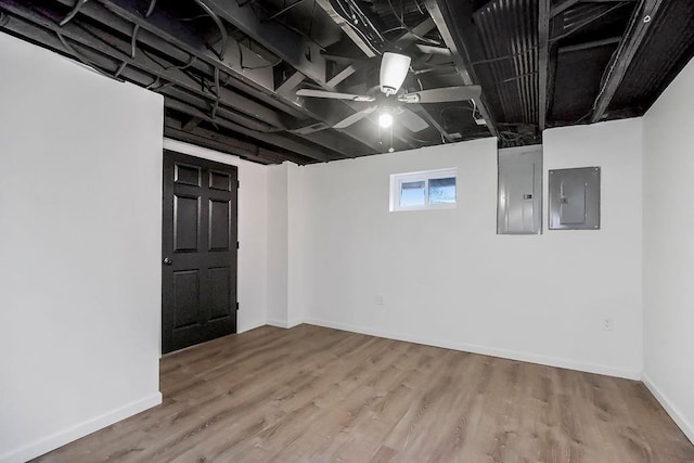 basement with wood finished floors, electric panel, and baseboards