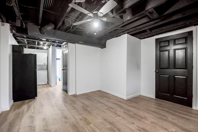 unfinished below grade area featuring light wood-style floors, baseboards, and freestanding refrigerator